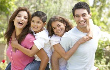 Happy family of four enjoying a sunny day in a park.